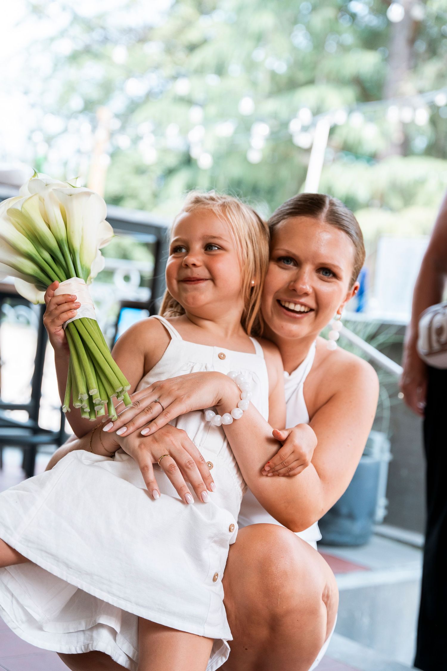 A touching moment with white calla lilies at an outdoor celebration.