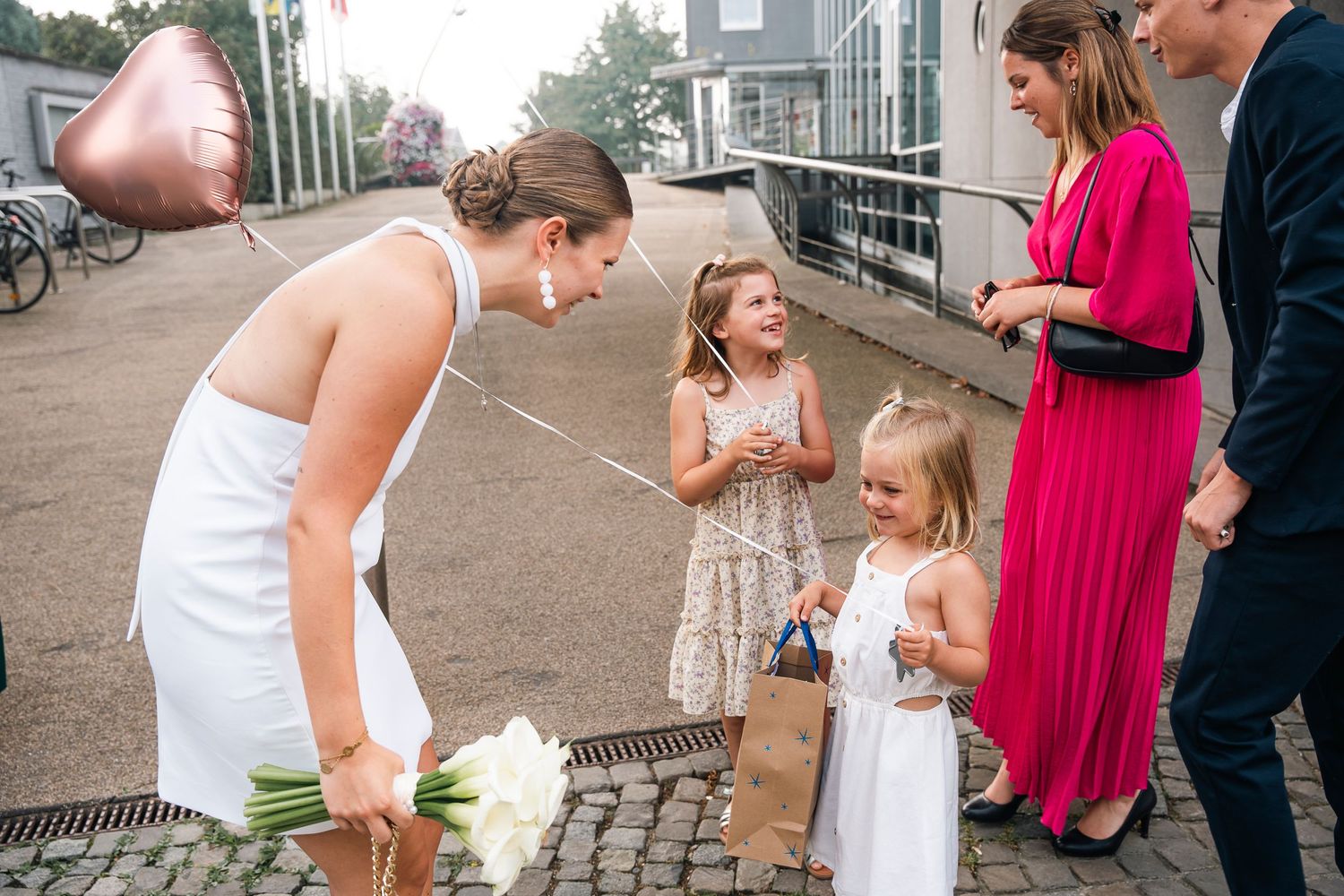 A sweet moment between wedding guests and children on a street.