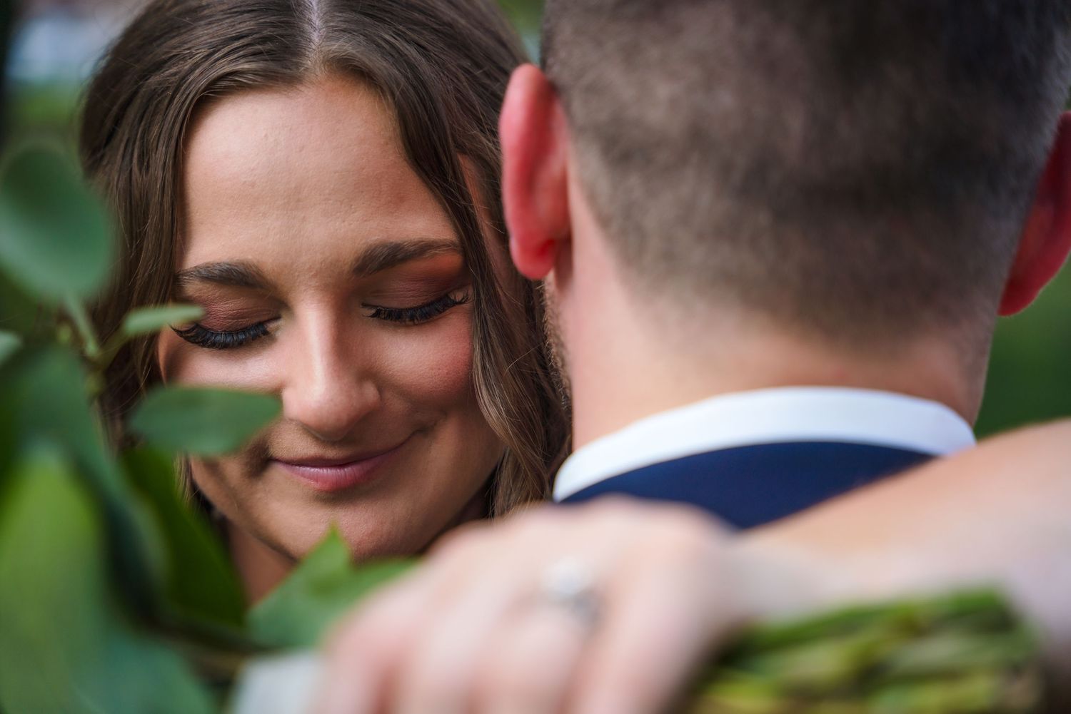 Intimate romantic moment captured among green foliage in natural lighting.