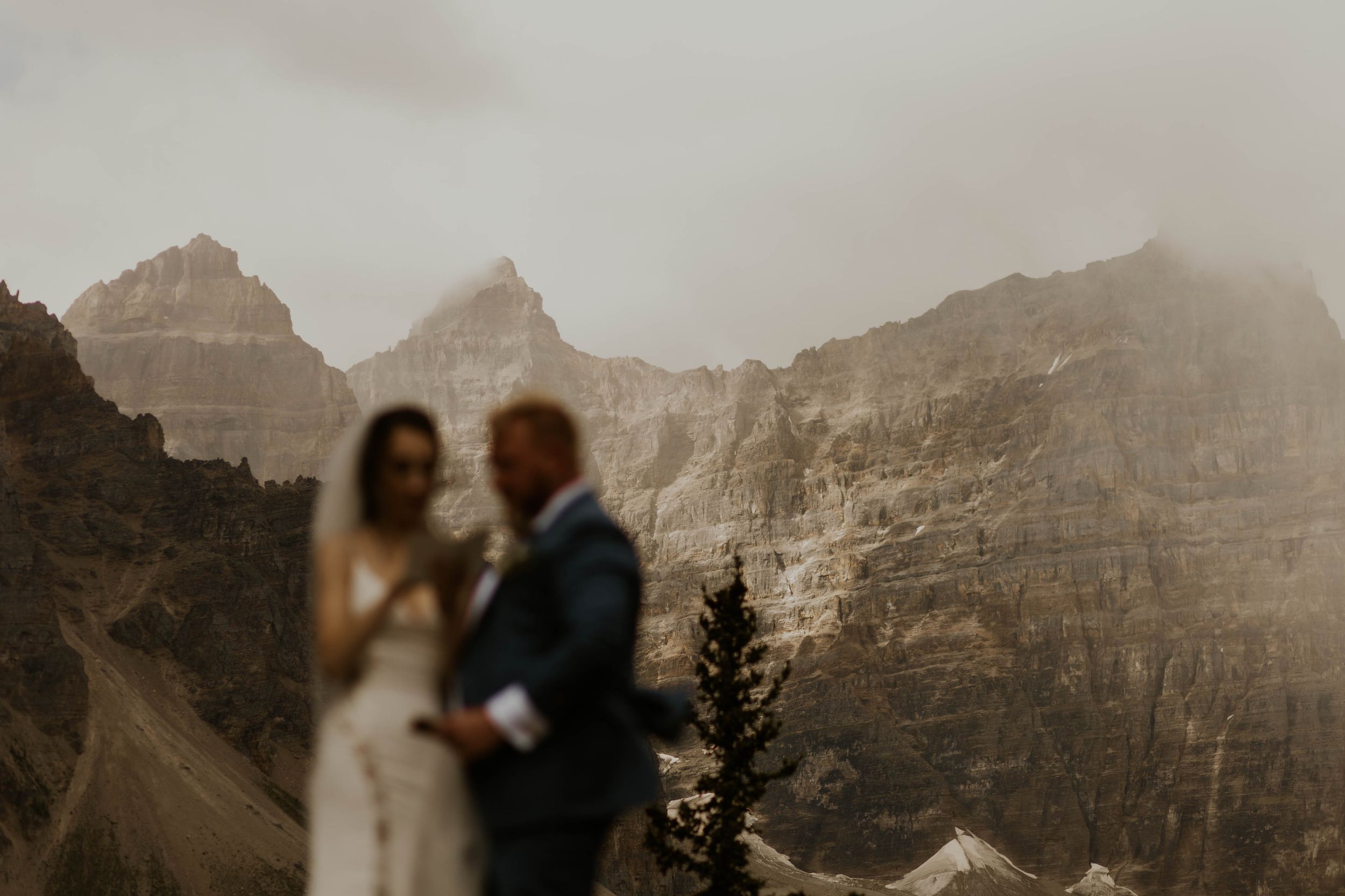 A dramatic mountain landscape serves as backdrop for an intimate moment between two people.
