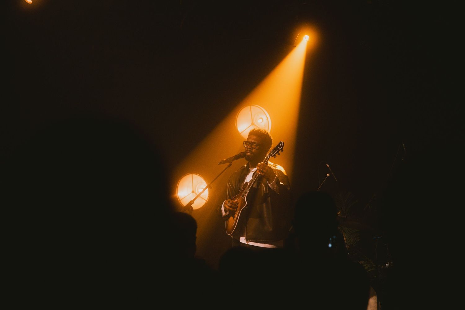 A dramatic spotlight illuminates a performer on a dark stage. Tour in Berlin Germany Jake issac
