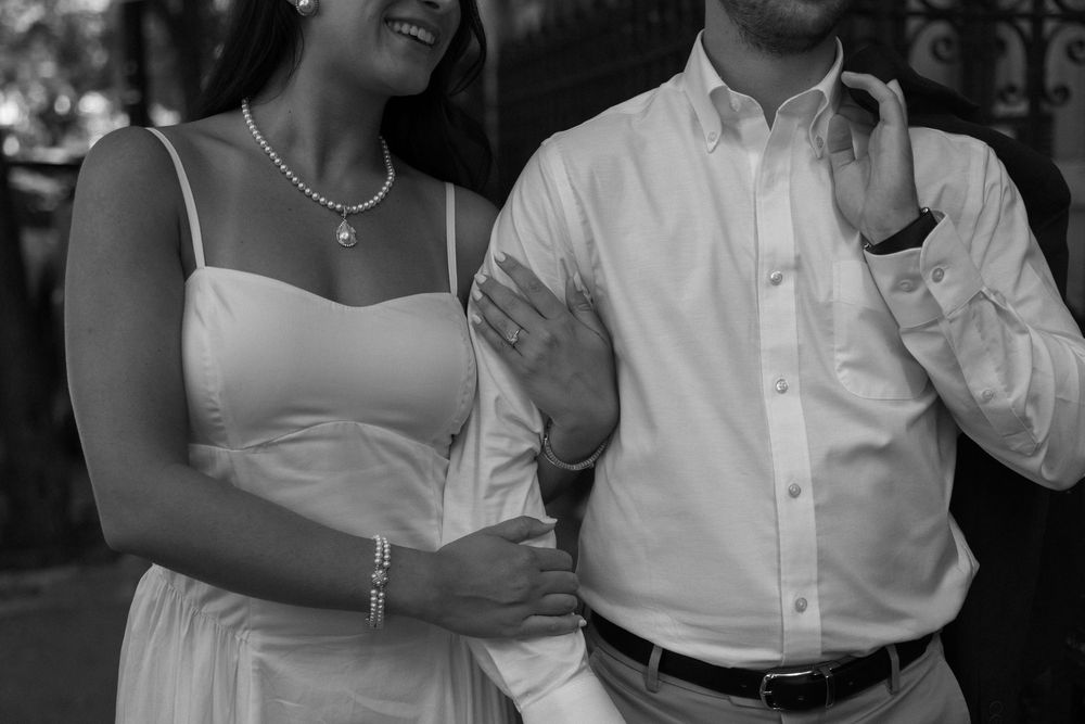 Black and white photo of a couple in wedding attire smiling and embracing during a celebration.