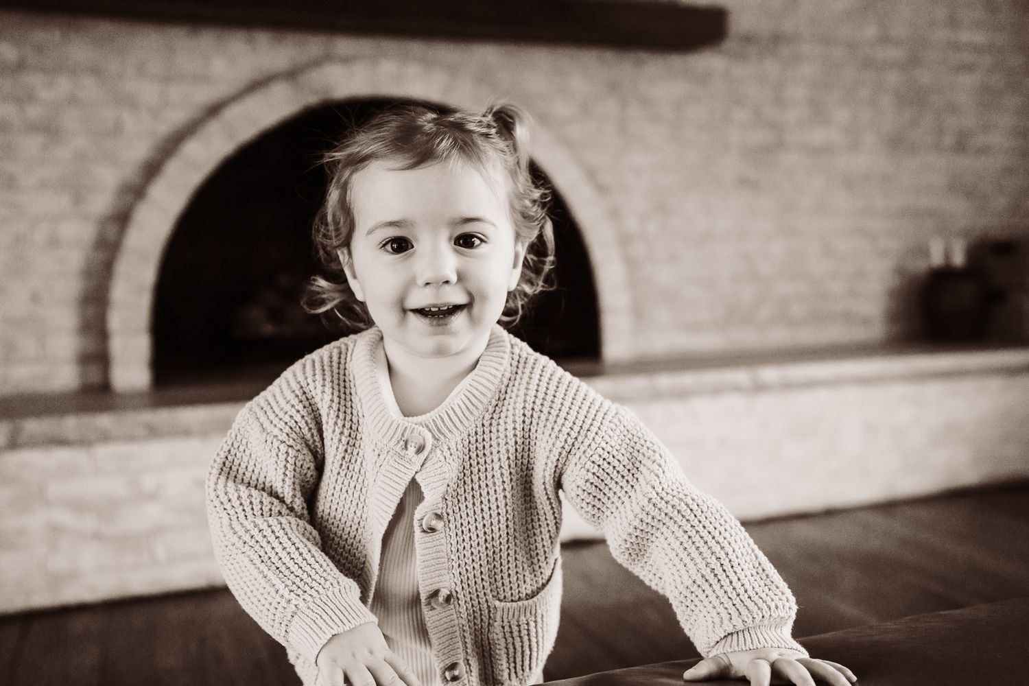 A young child in various poses and expressions on a brick background during lifestyle newborn session in Barrington.