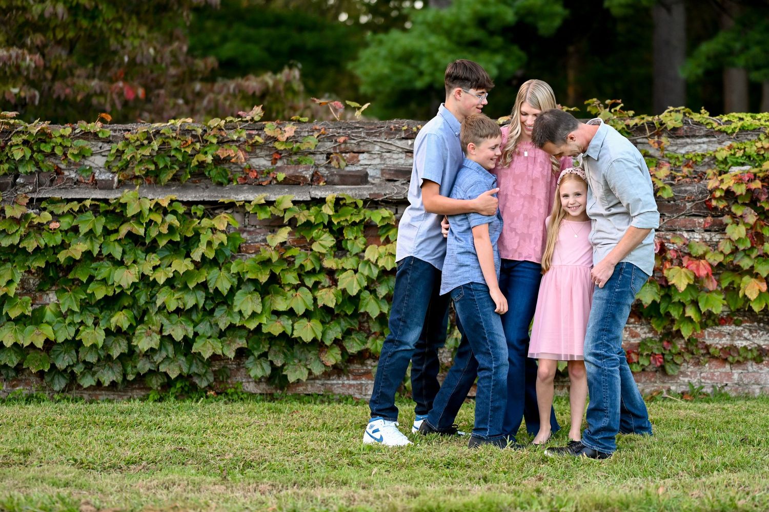Family enjoying a playful moment together in a garden setting with ivy-covered walls.