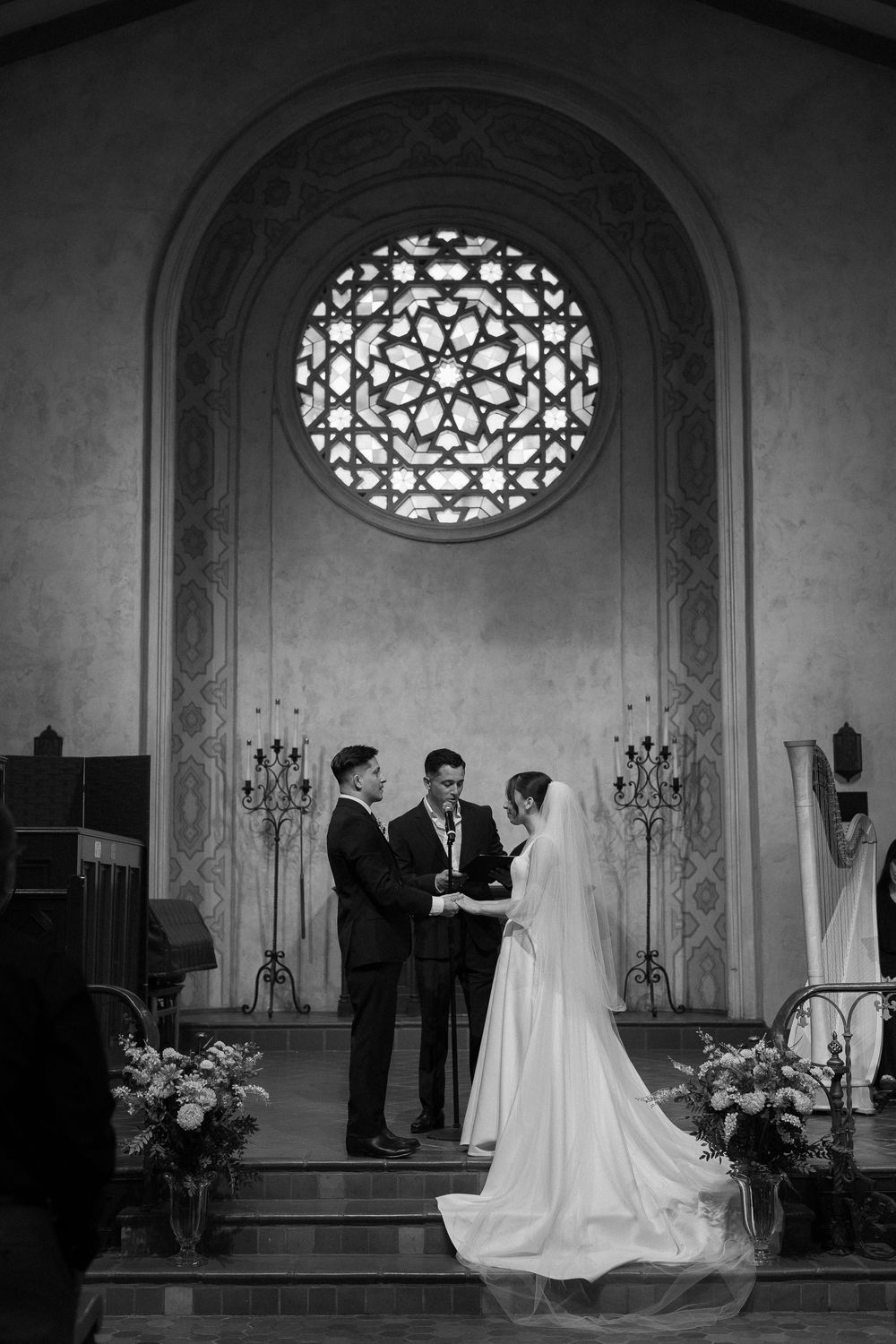 A black and white Unitarian Society photo with the bride and groom holding hands in a historic Santa Barbara chapel.