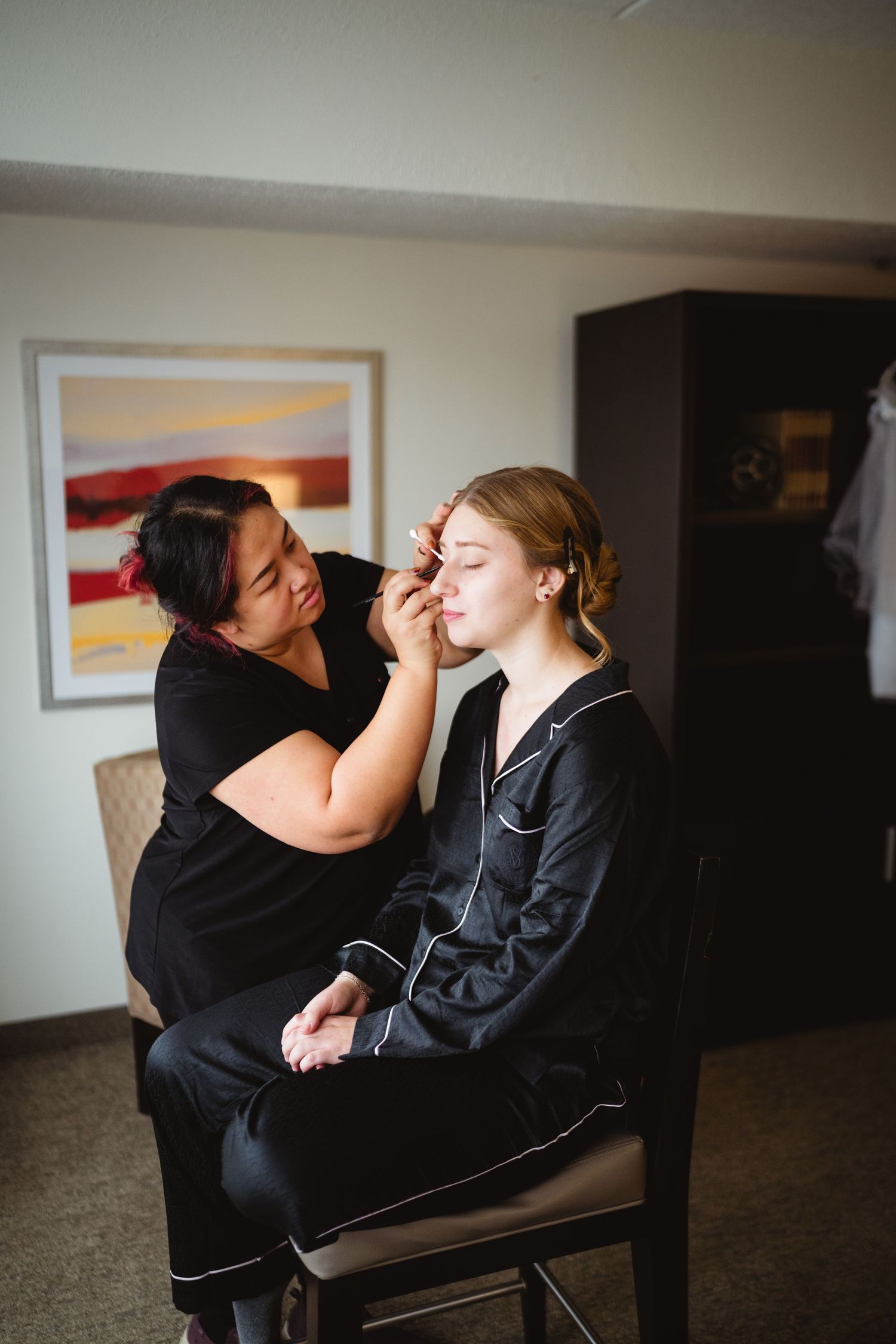 A makeup artist applies cosmetics to a client in a series of four sequential photos showing the application process.