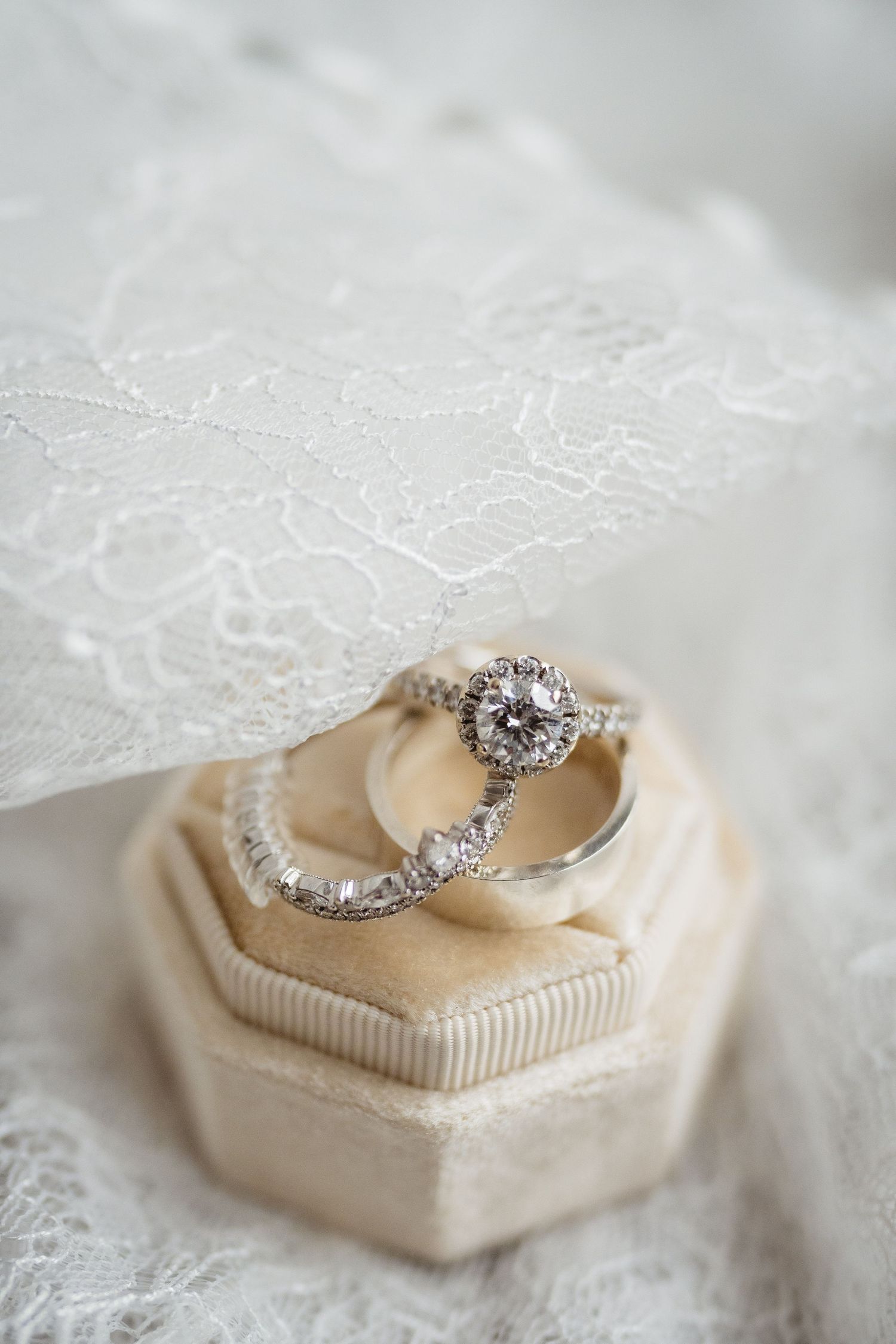 Diamond engagement ring rests on a cream-colored cushion with delicate lace details.