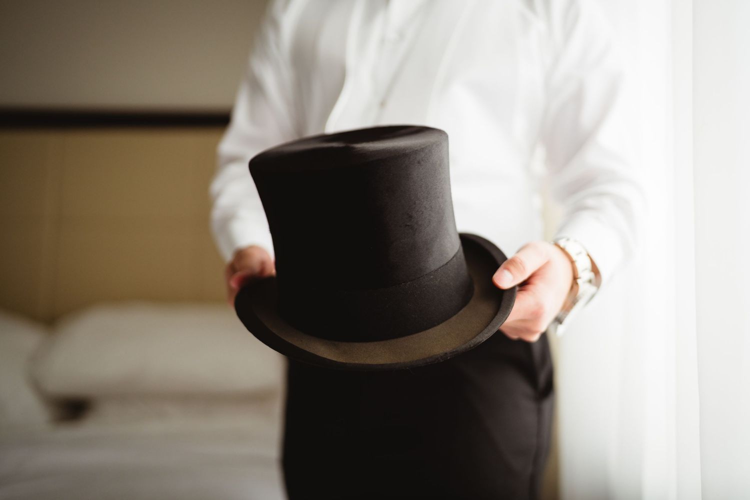 A black top hat held against a white dress in multiple cropped views showing different angles and perspectives.