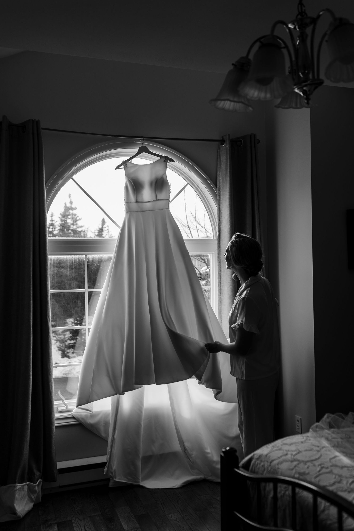 A ghostly figure draped in white fabric floats near a window in a dark room creating an eerie Halloween scene.