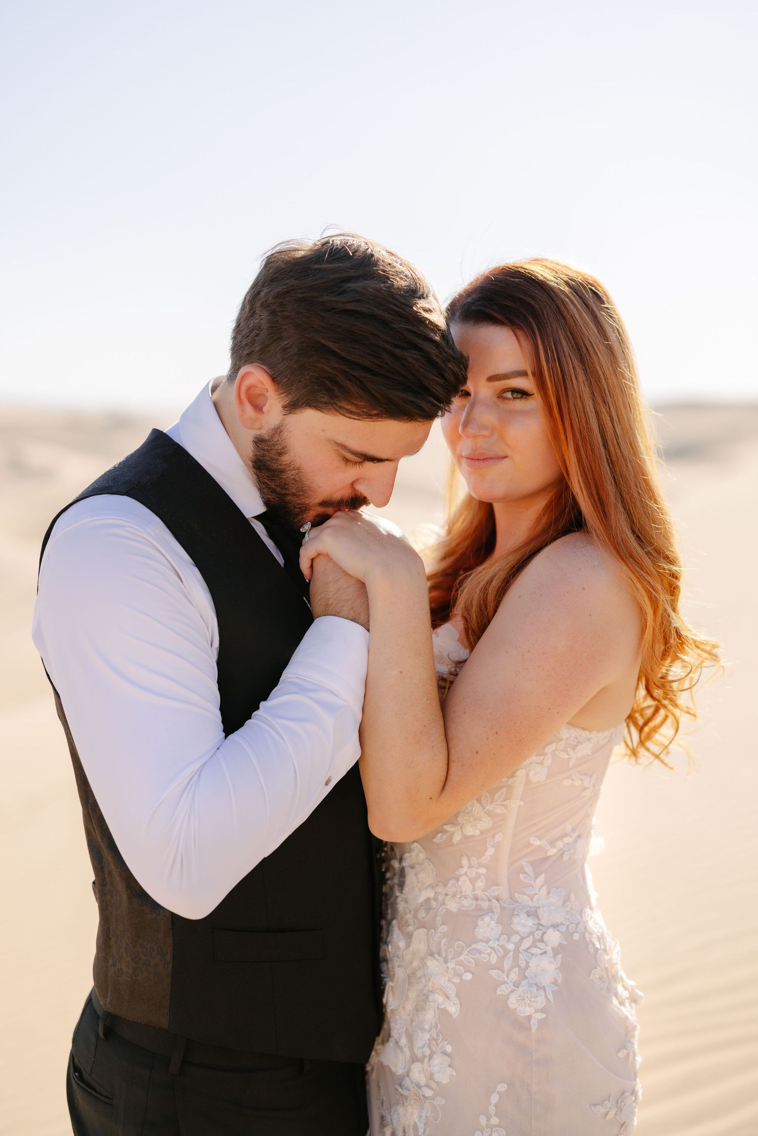 A happy couple in wedding attire share a tender moment during their outdoor photo session.