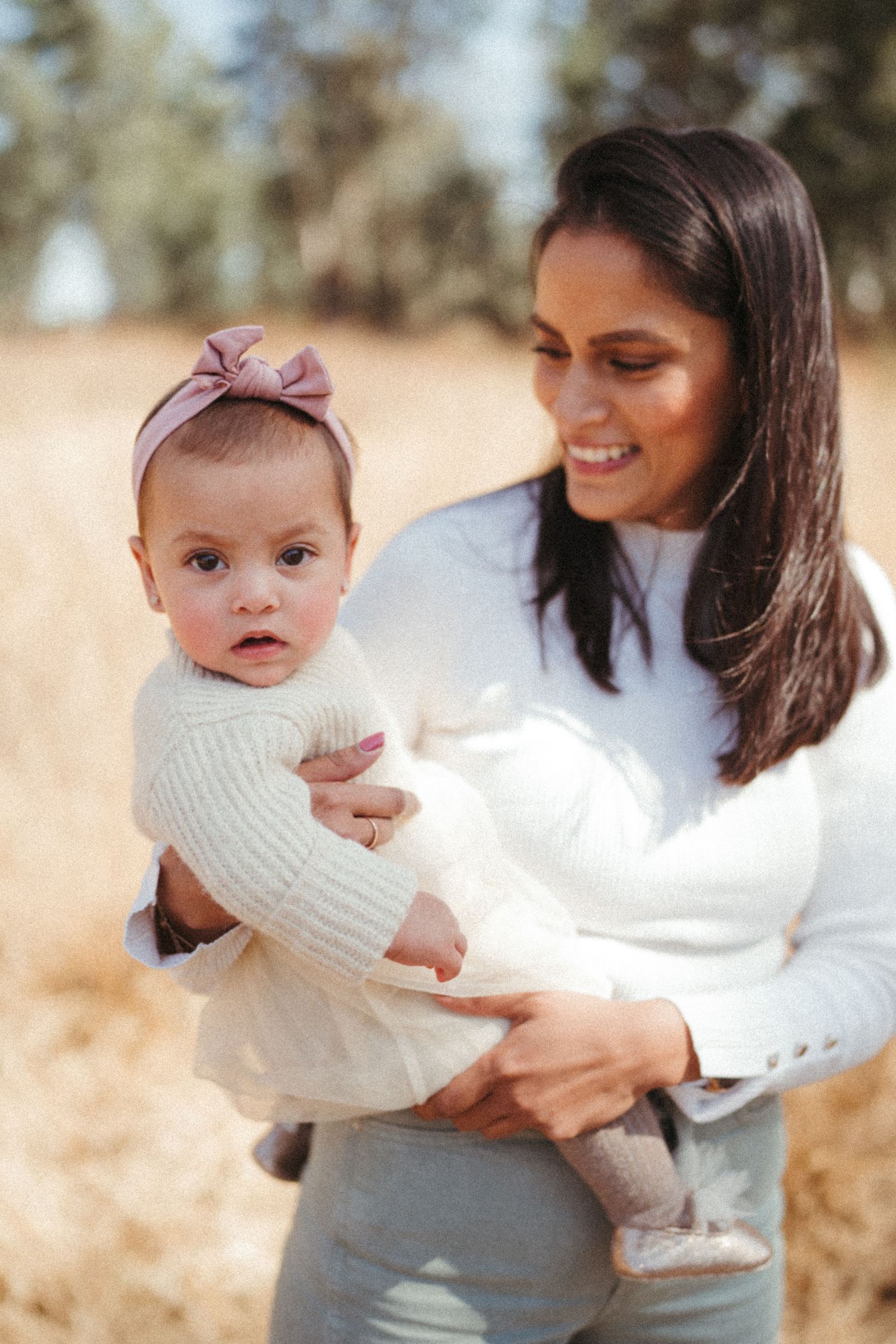Sweet moments between parent and baby in white sweaters outdoors.