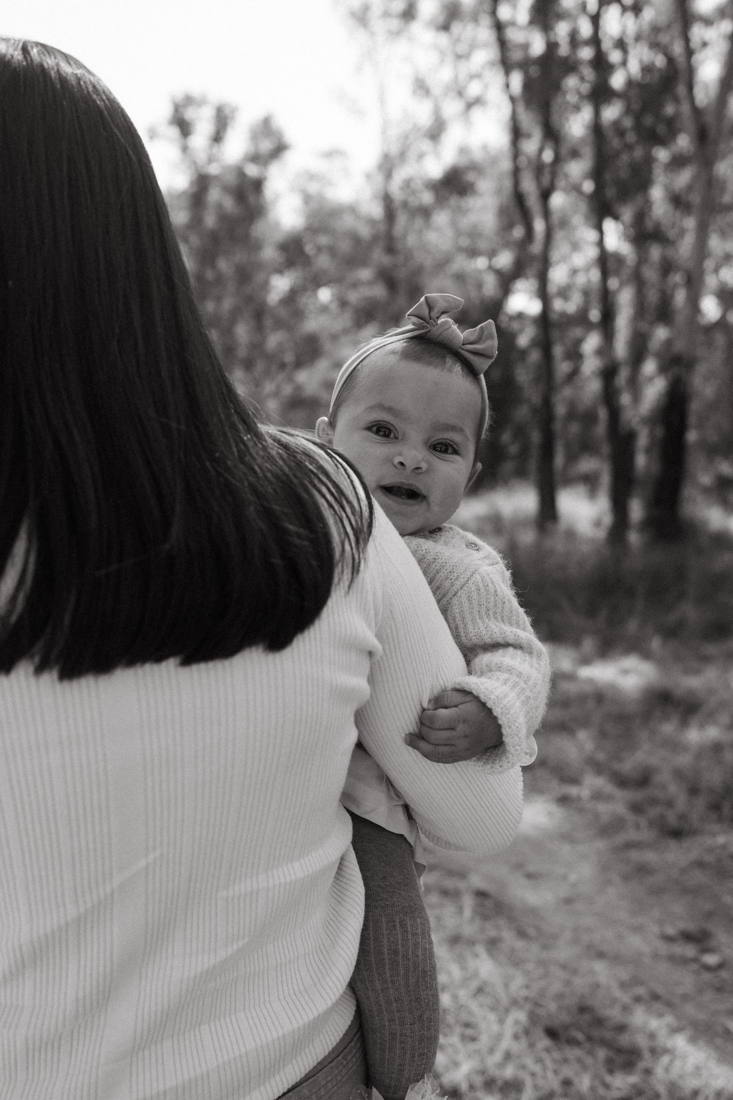 Black and white series of parent holding baby on nature trail.