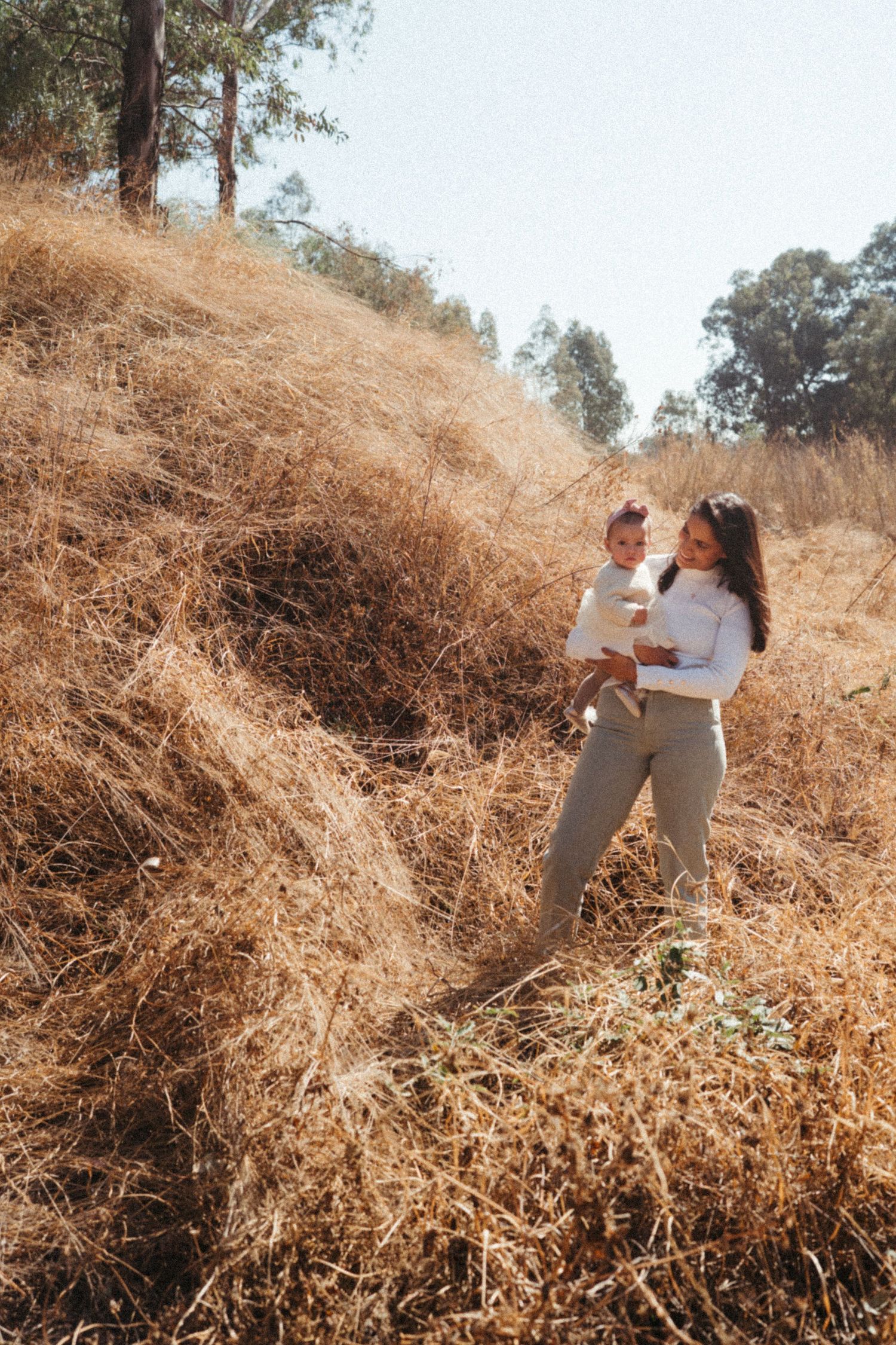 Family enjoying a candid moment together on a golden hillside during sunset.