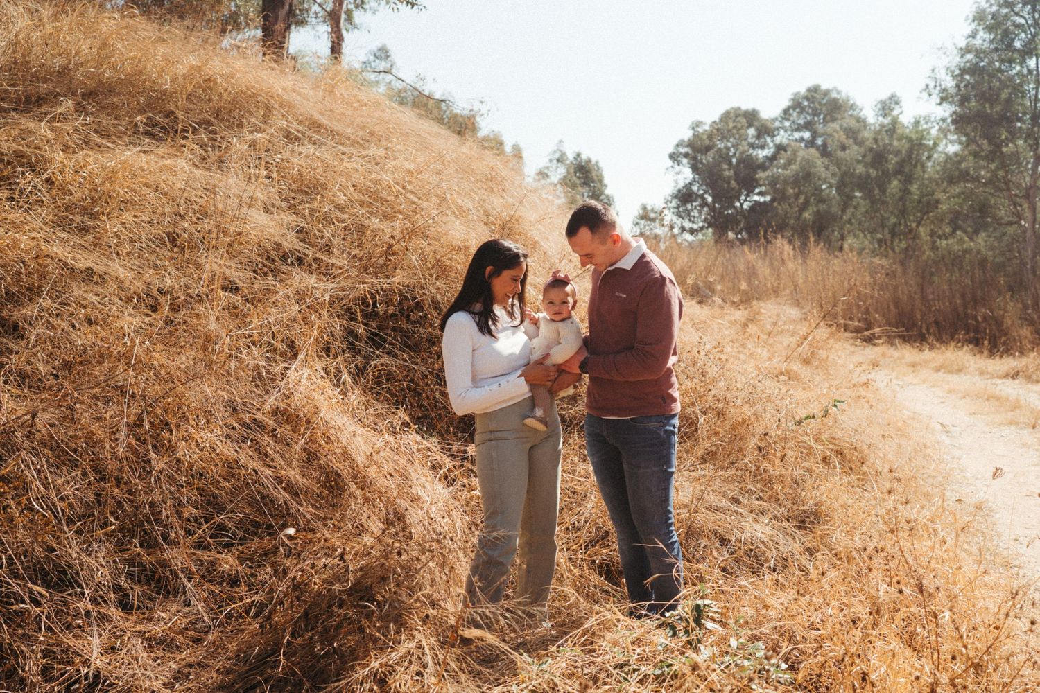 Candid family interaction captured on a golden hillside during magic hour.