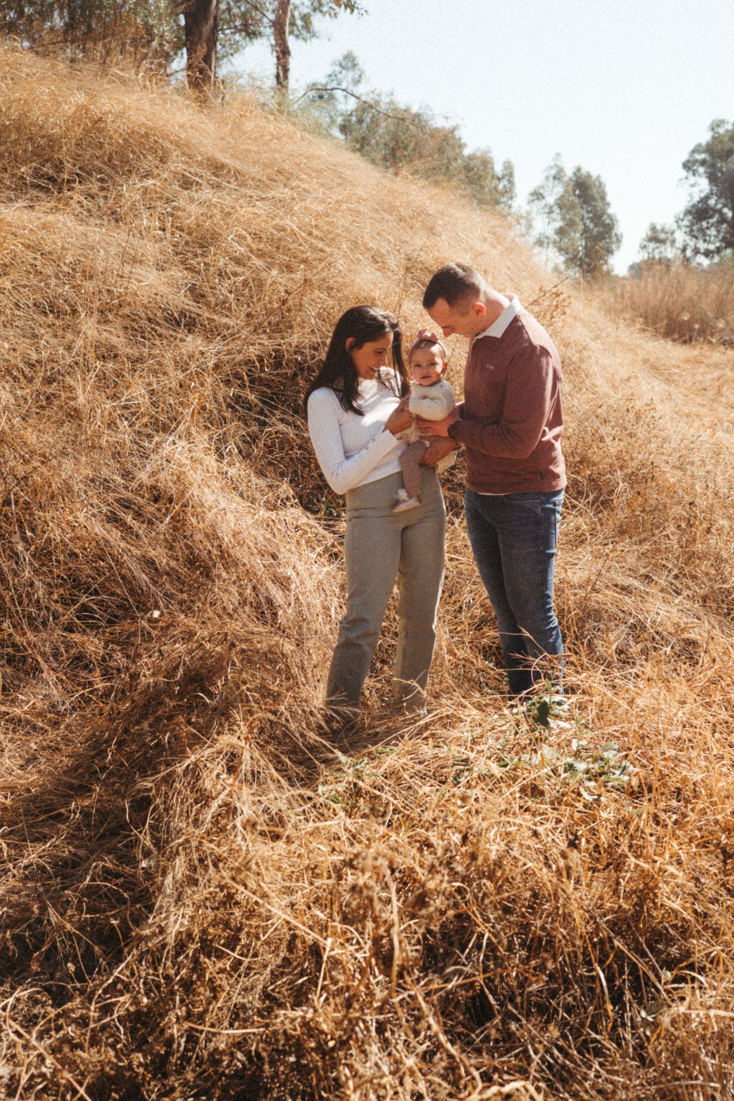 Family sharing joyful moments together on a sunlit hill with dried grass.