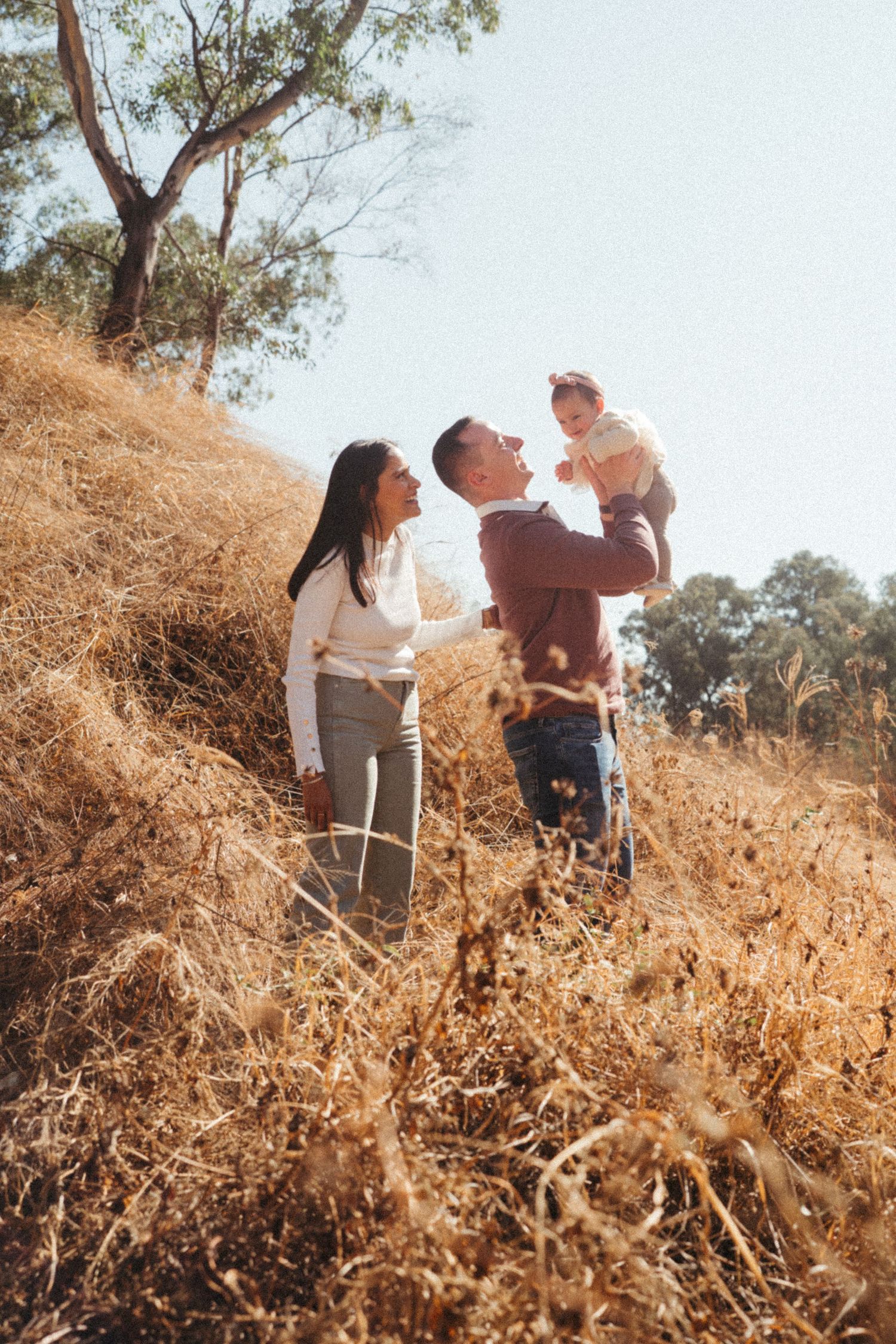 Natural family moment photographed on a hill with golden afternoon light.