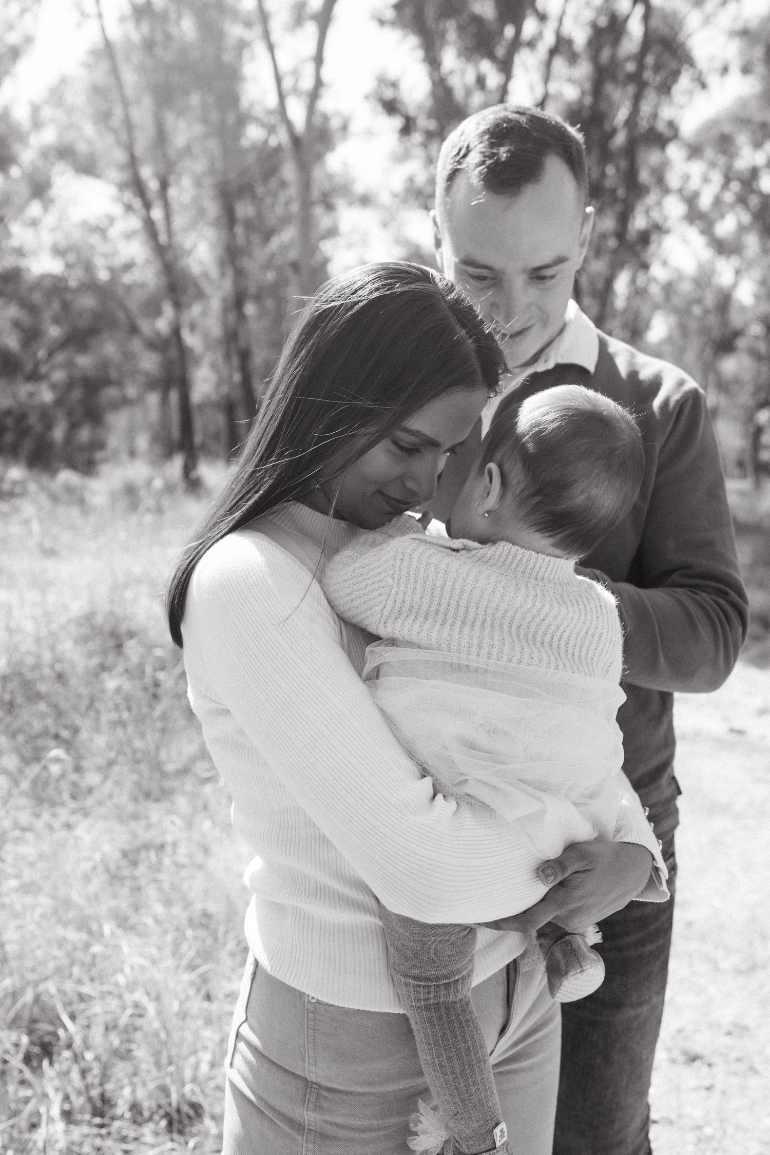 Black and white series showing tender family moments in a natural setting.