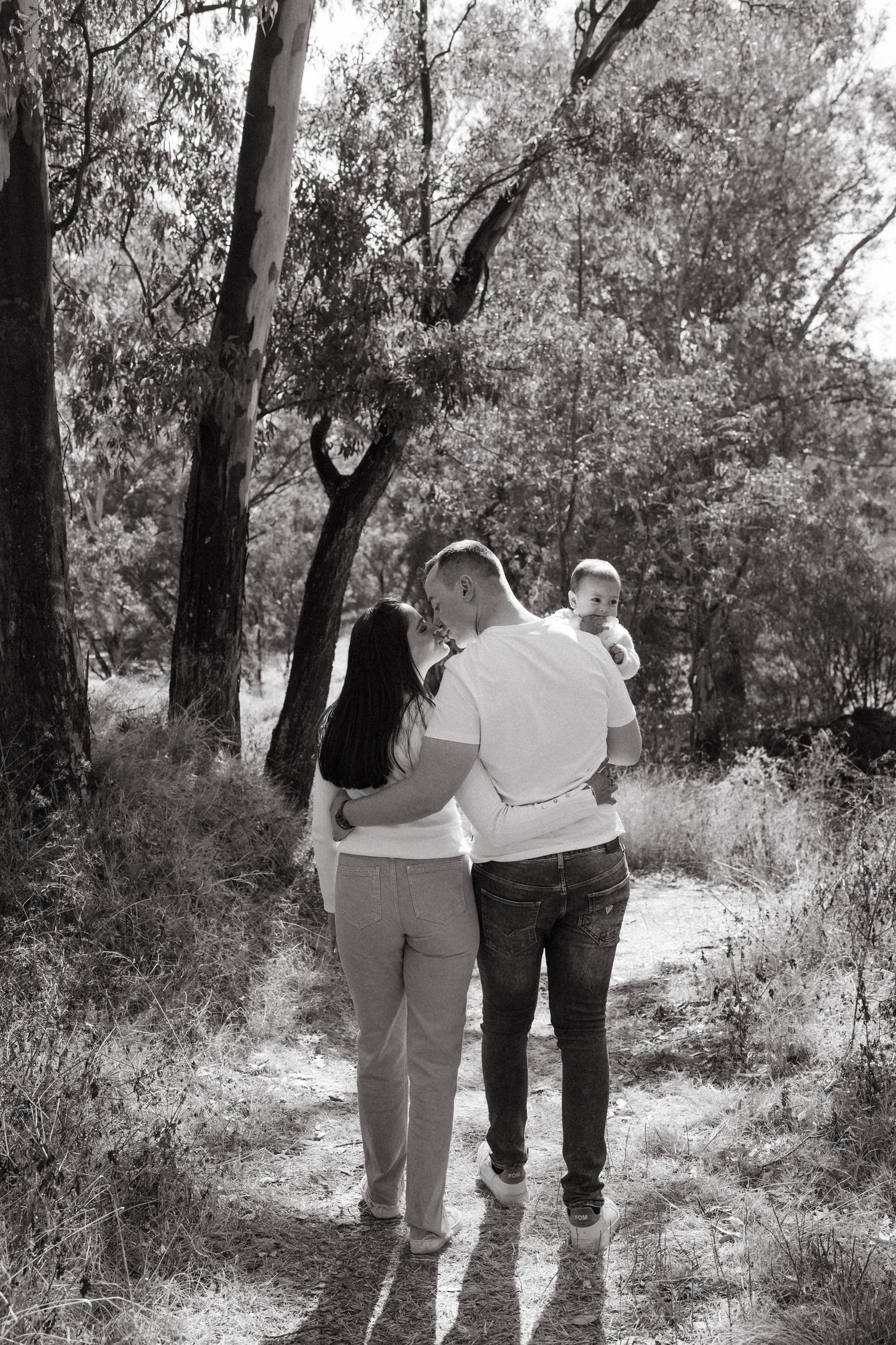 Black and white photo of family walking together on a wooded path.