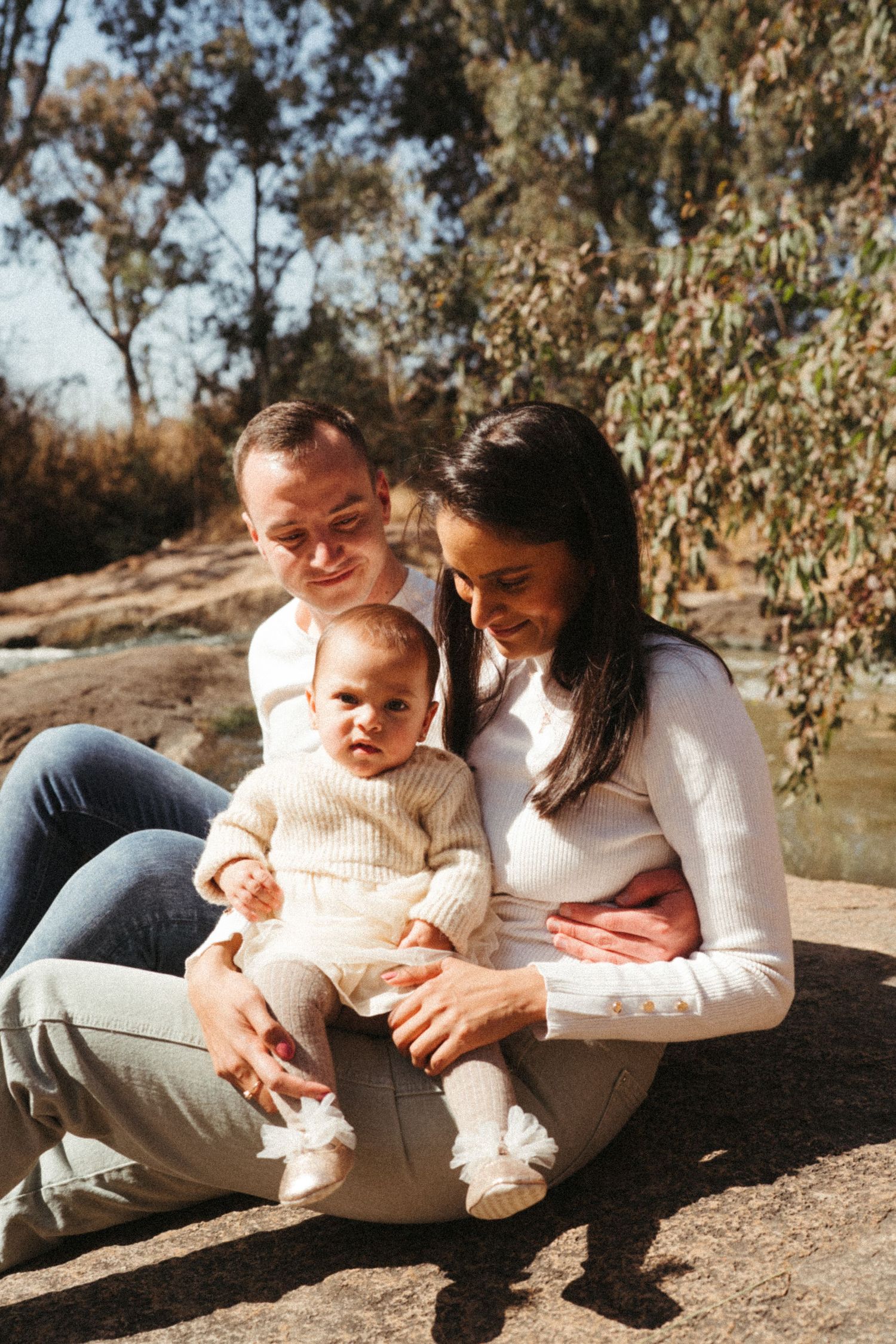 A tender outdoor photoshoot showing loving family moments on rocky terrain in natural lighting.