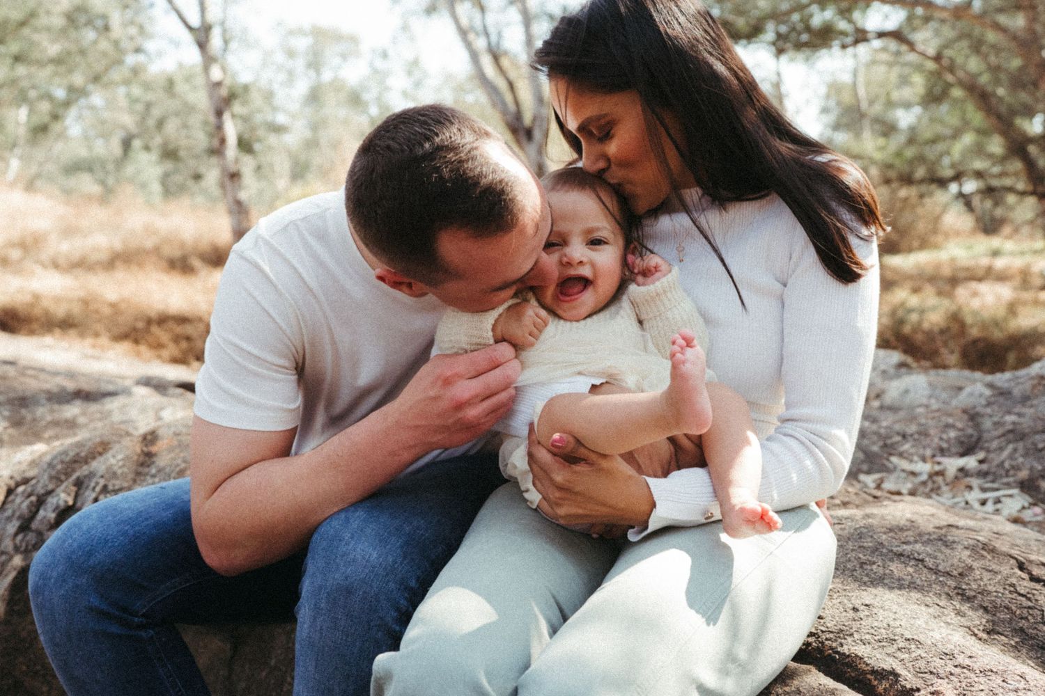 Sweet candid moments of a family sharing affection outdoors in warm sunlight.