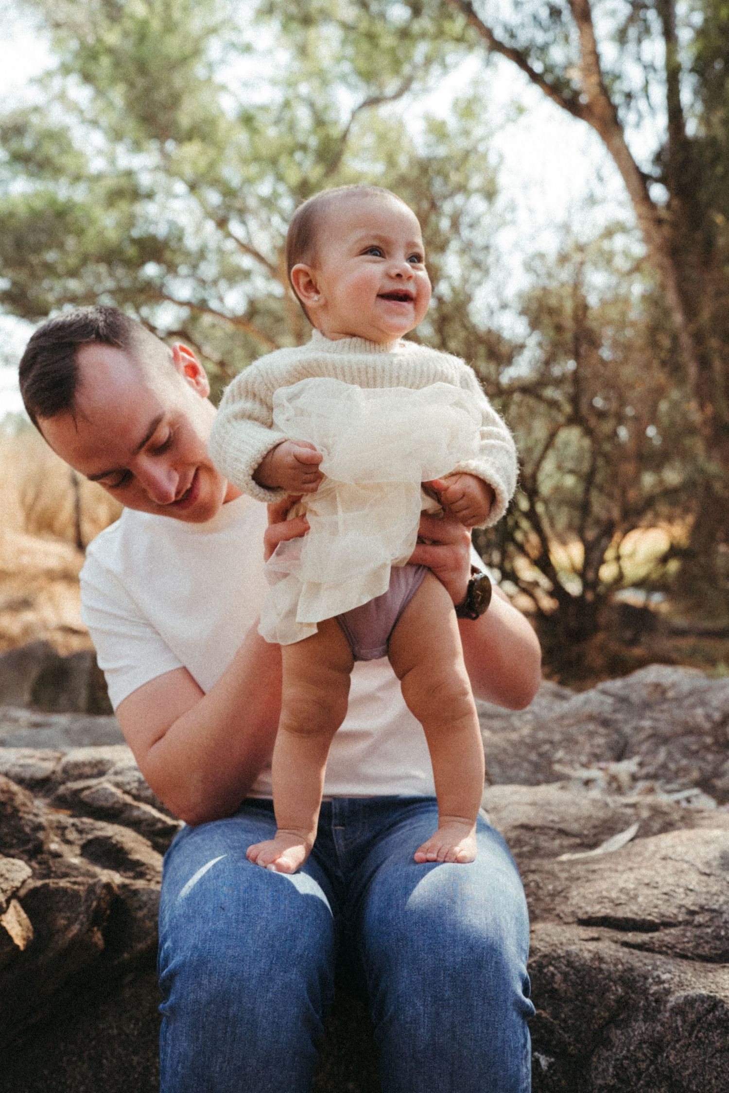 Joyful outdoor photoshoot showing playful moments between family members on rocky terrain.