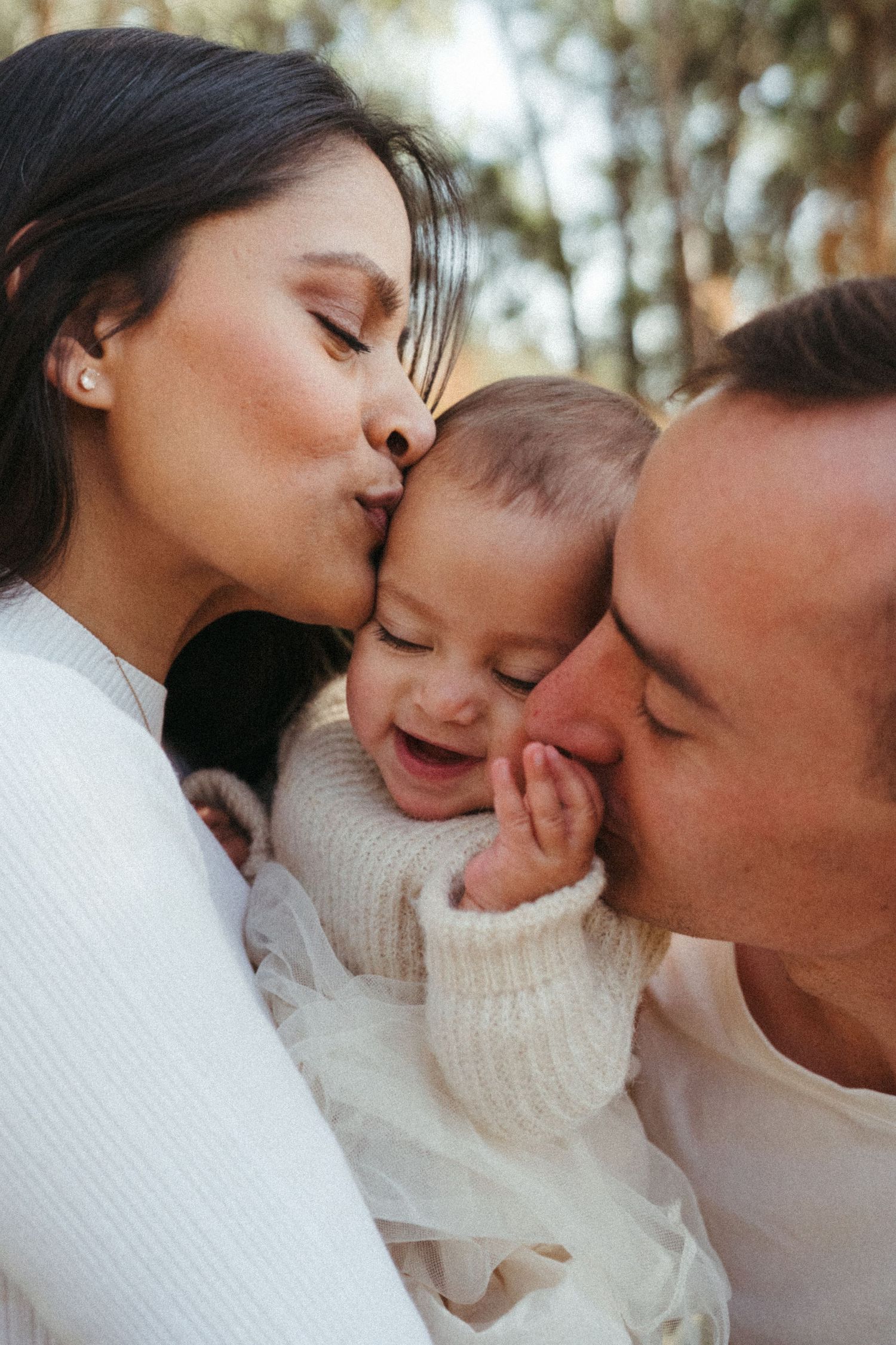 Sweet family embrace captured in soft natural lighting outdoors.