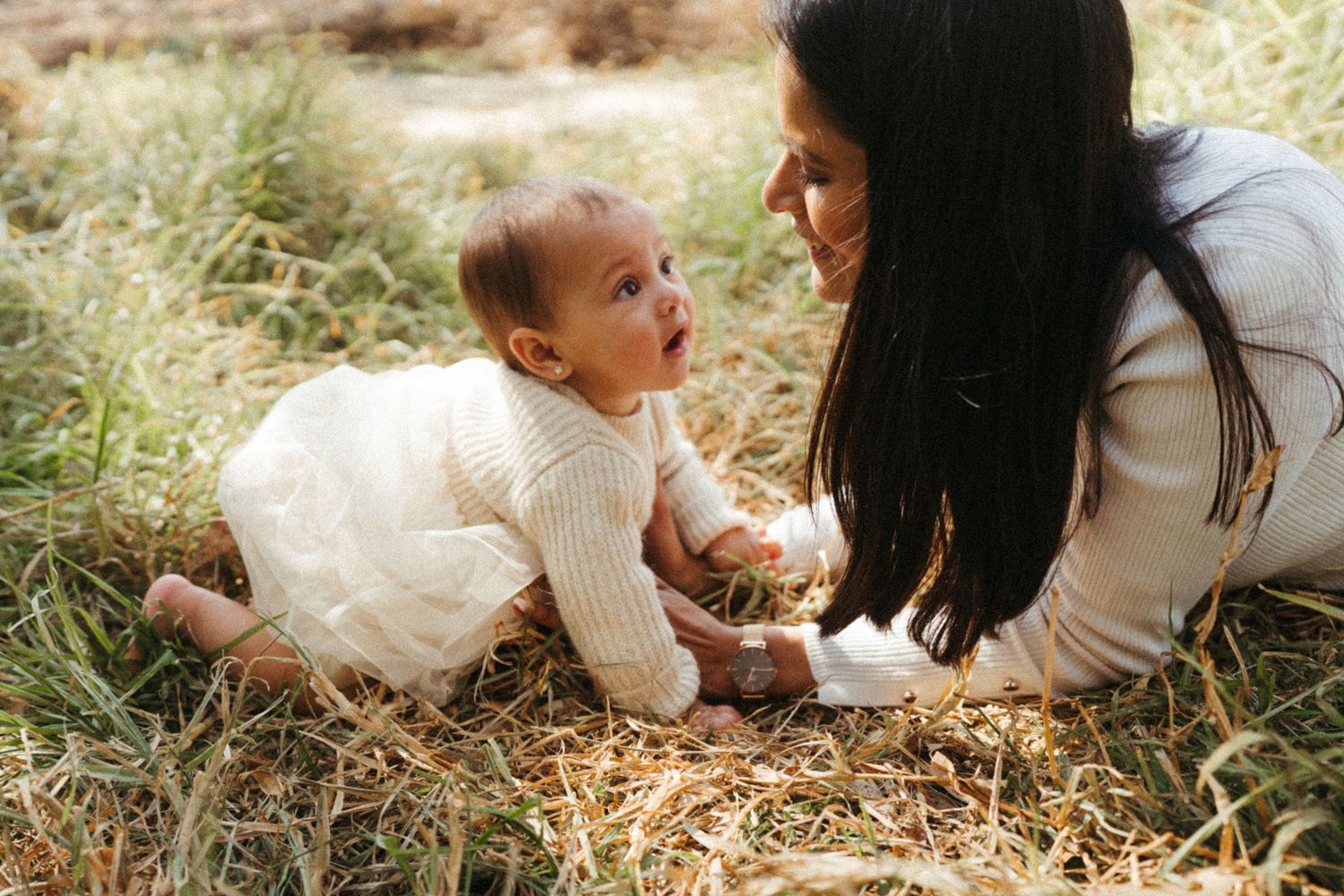 Family playtime captured in warm sunlight on grassy field.