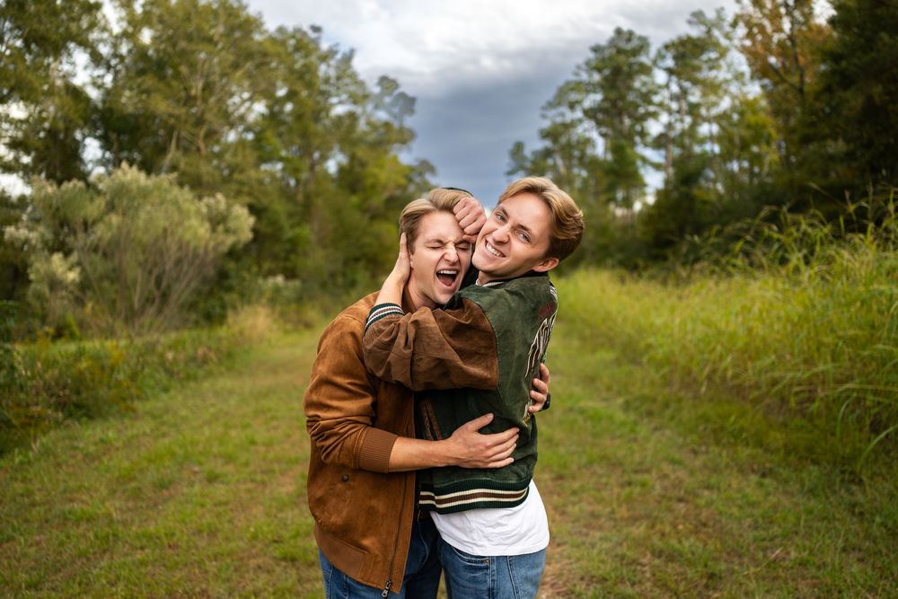 Candid moment of two people laughing and embracing while wearing matching brown jackets outdoors.