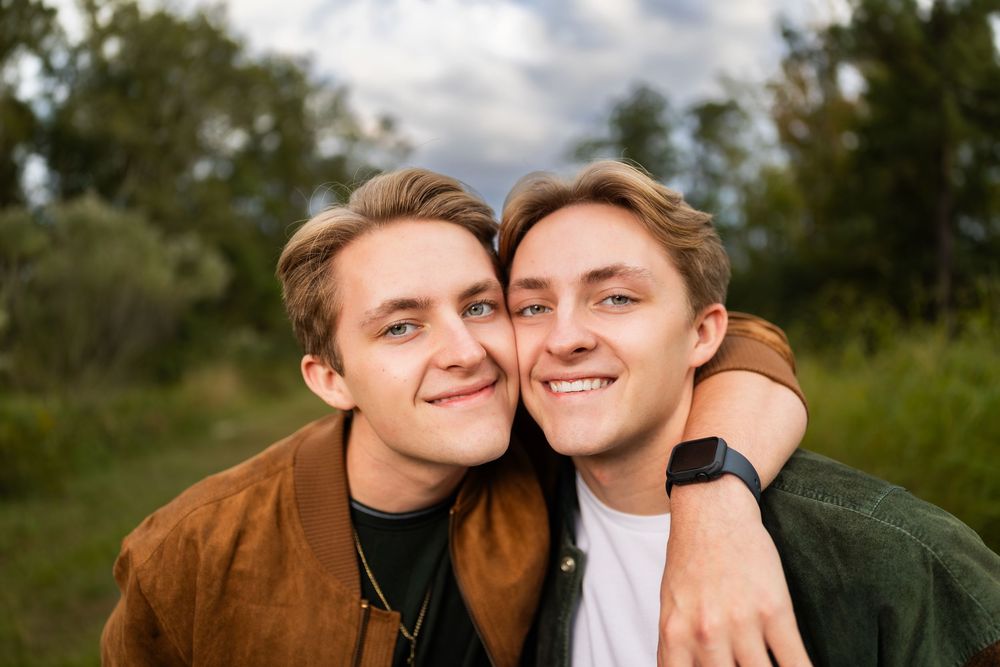 Two people sharing a warm embrace while smiling outdoors on a cloudy afternoon.