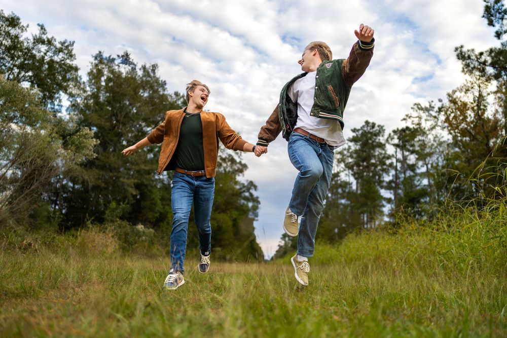 Dynamic shot of people leaping and playing on grassy hillside under cloudy sky.
