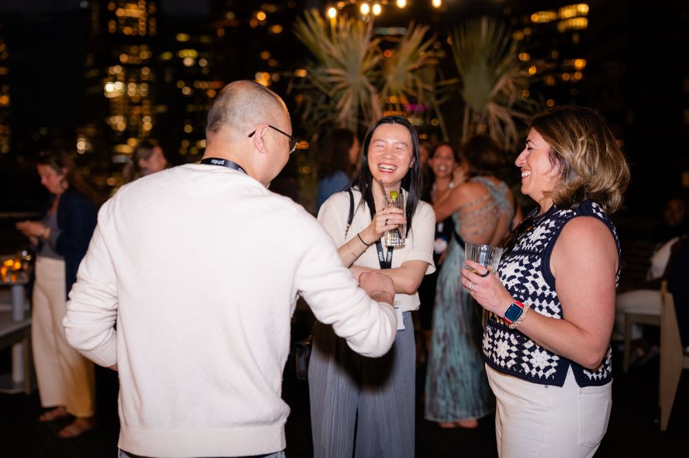 Guests mingling and laughing at an elegant evening networking event with tropical decor and ambient lighting.