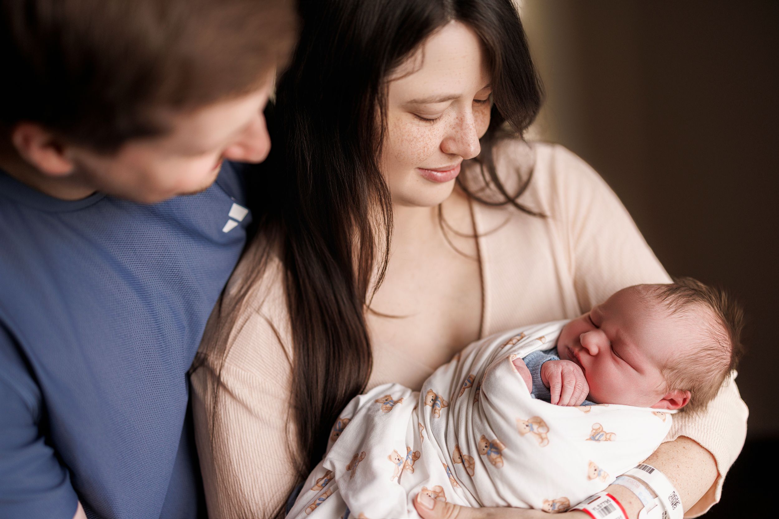 Tender family moment captured in warm lighting as parents share intimate cuddles with their young children.