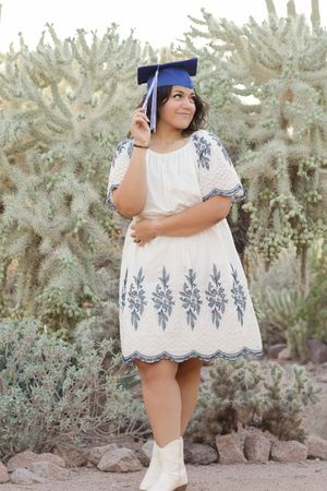 Light and airy senior photo of a girl smiling with her graduation cap on her head at Desert Botanical Garden in Phoenix, Arizona.