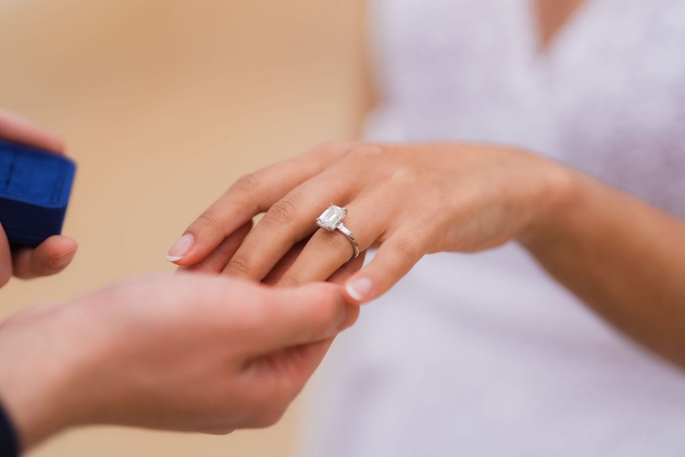 Close-up view of hands exchanging wedding rings during a marriage ceremony.