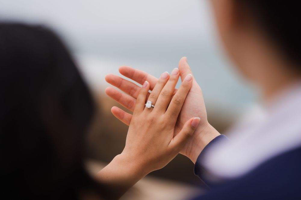 A close-up shot of hands exchanging rings during an outdoor wedding ceremony.