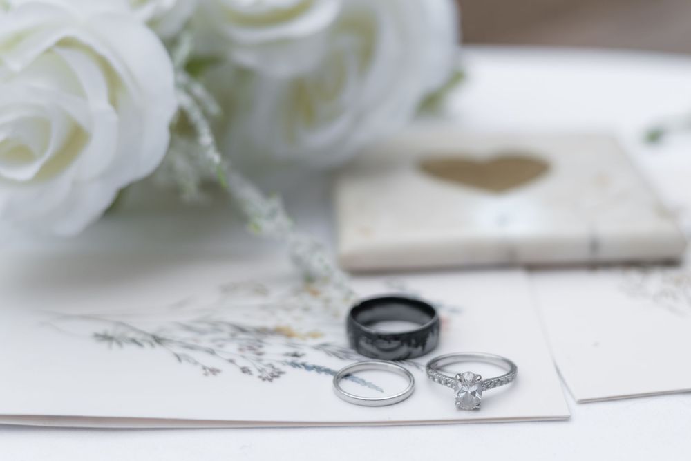 White roses and wedding rings displayed on paper with delicate romantic styling for wedding photography.