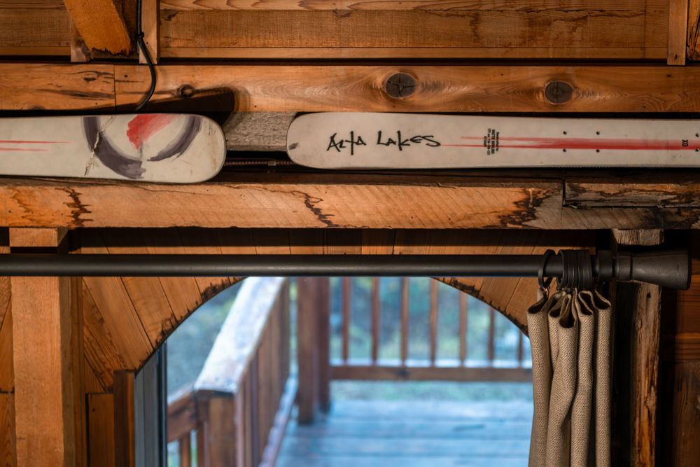 Rustic wooden ceiling beams create a warm, cabin-like atmosphere. Two skis sit on the top of the windows. Alta Lakes is written on the skis.