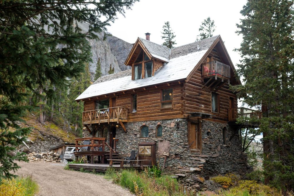 An image of the Observatory at Alta Lakes in the fall on a cloudy moody day. Pine trees are around the two story rustic cabin.
