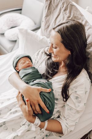 A series of intimate photos showing tender moments between mother and baby lying together on white bedding.
