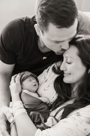 Black and white photos show tender moments between parents and their newborn baby in a hospital setting.
