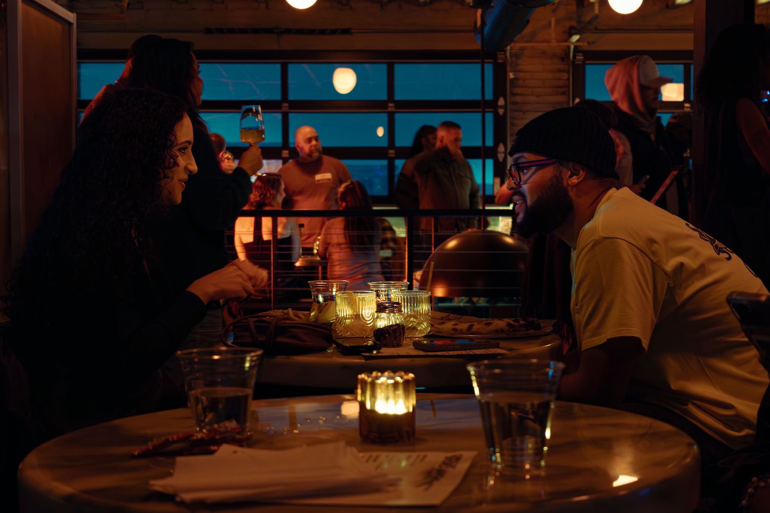 People dining at a cozy restaurant table illuminated by candlelight.