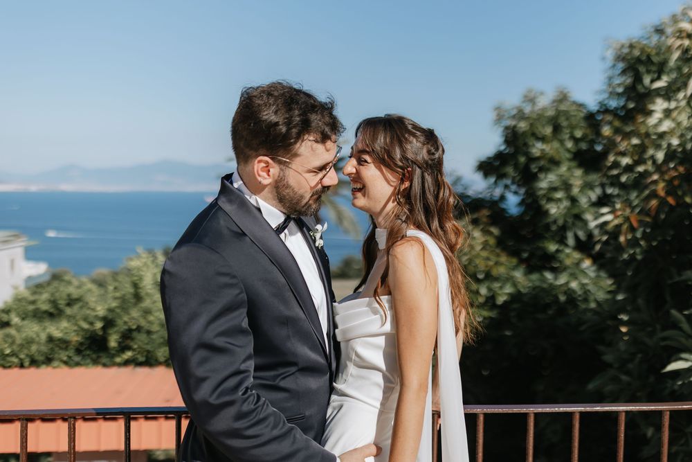 Couple shares intimate moments during coastal wedding photoshoot with ocean views and lush greenery.