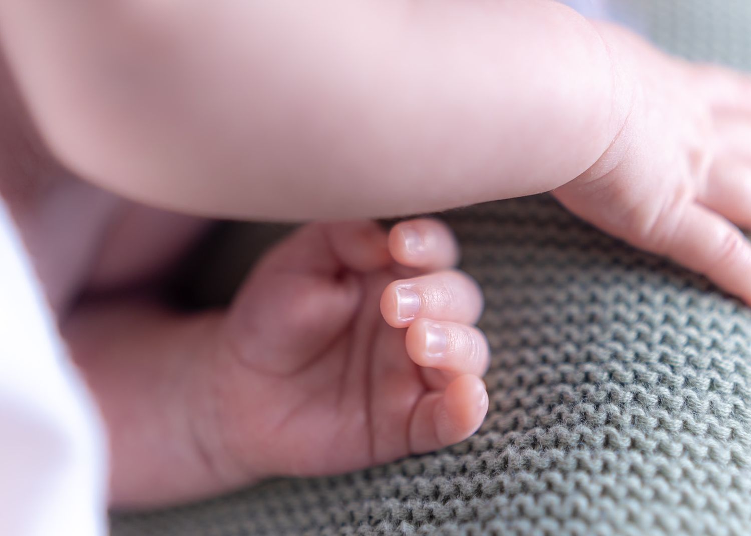 Close up of tiny baby toes on gray knit blanket.