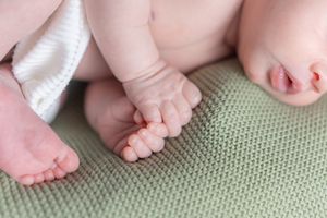Close up of tiny baby feet and toes on textured green fabric.