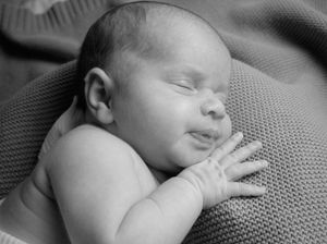 Peaceful sleeping newborn in black and white on textured blanket.