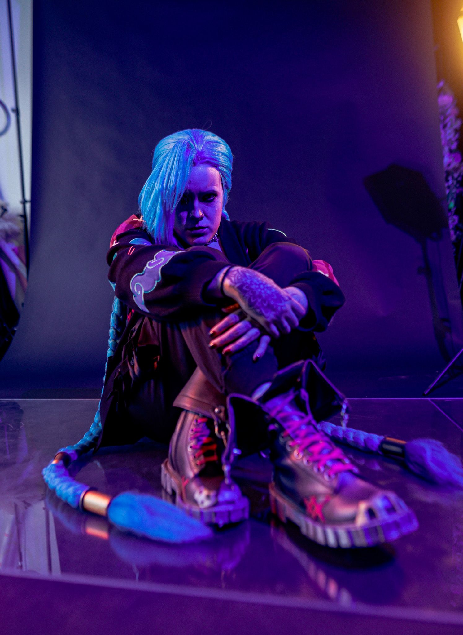 Close-up of sneakers illuminated by purple and blue neon lighting on a dark surface.