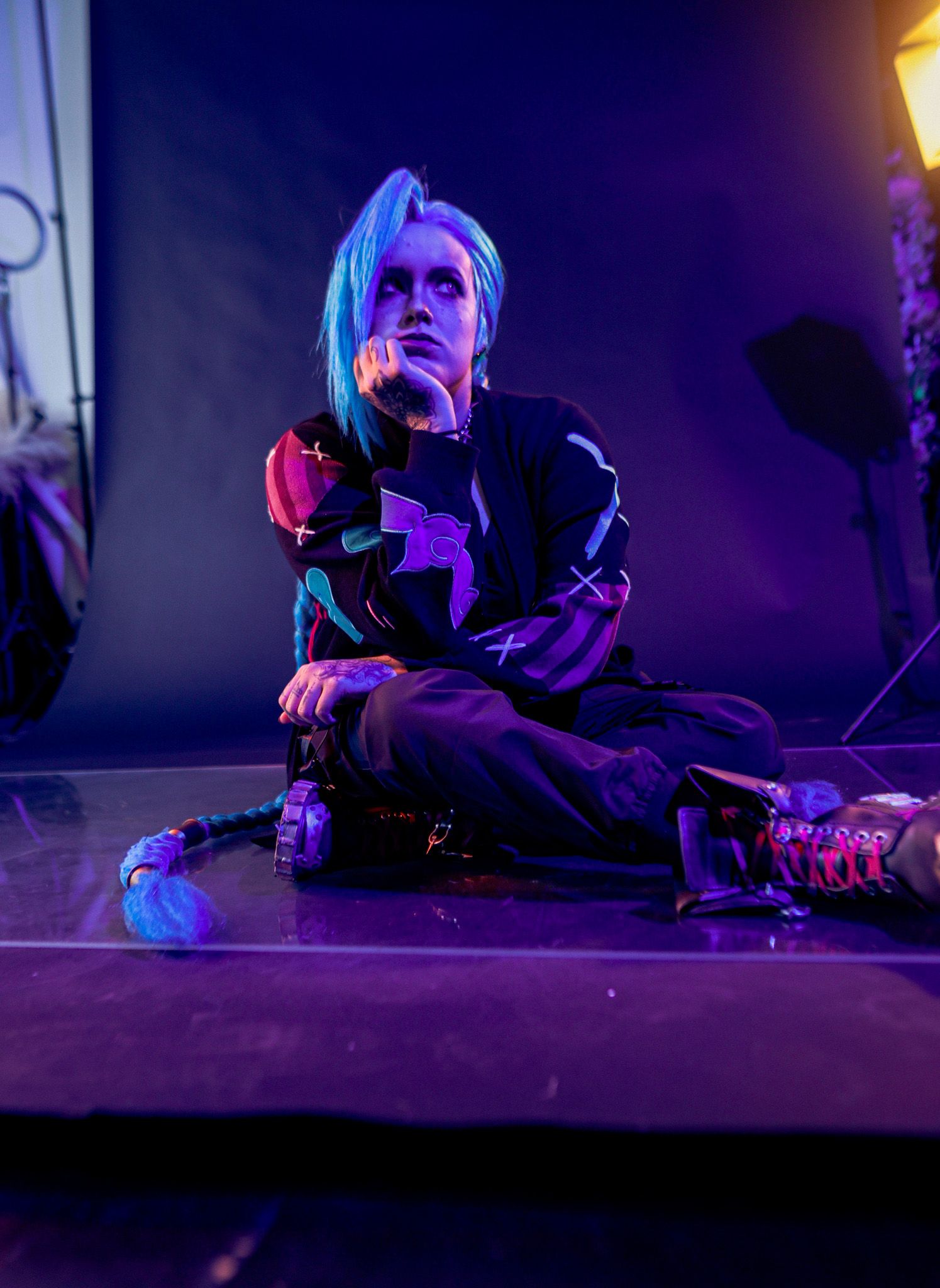 A person lies on a dark floor illuminated by dramatic purple and blue lighting in a cinematic composition.
