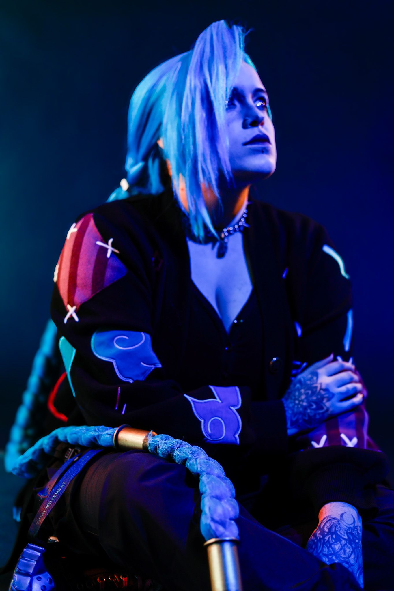 Artistic concert photos in blue lighting show a performer in black clothing against a dark background.