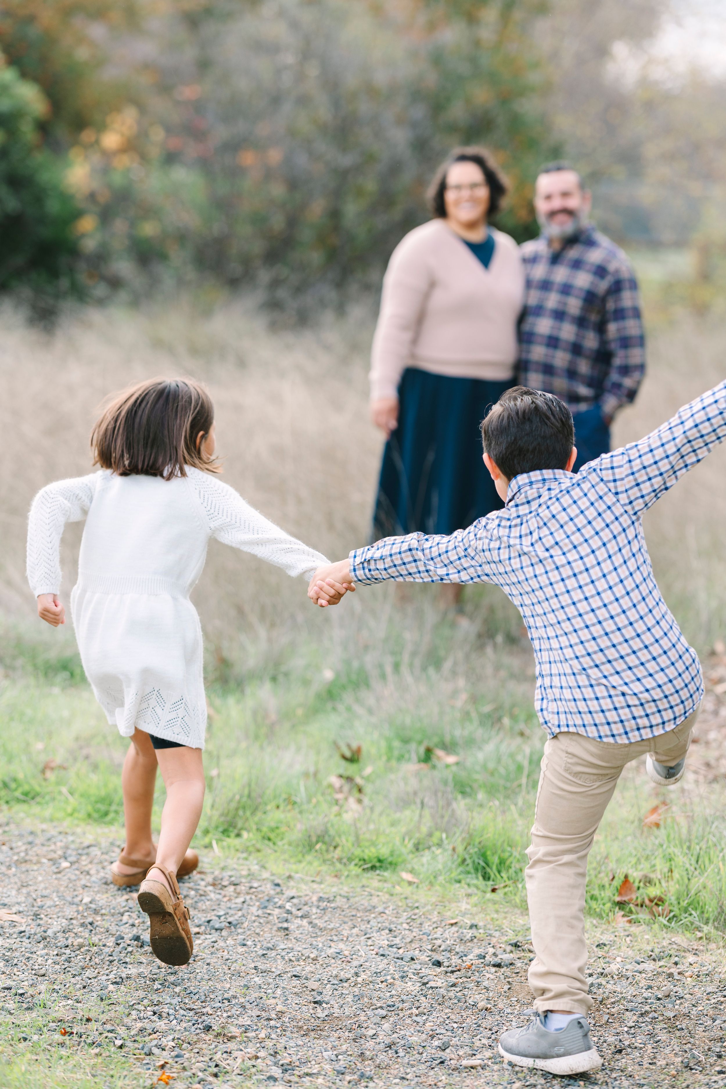 Children playing and running on a gravel path in a natural outdoor setting.