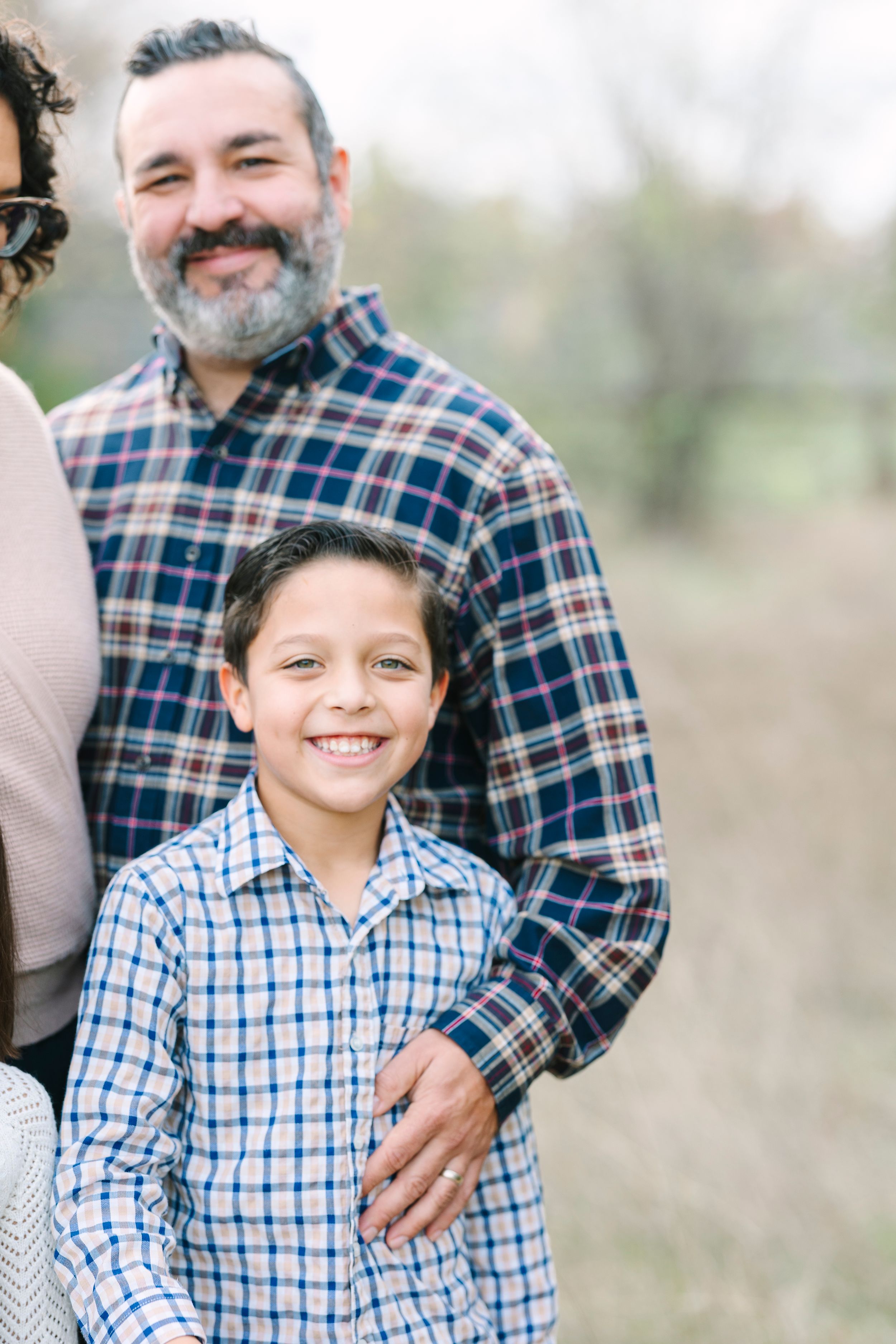 Family portrait outdoors with plaid shirts and casual attire.